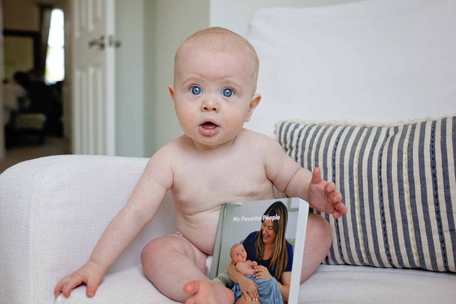 Baby holding album with images of his family and himself as a newborn. Images by Audrey blake Photorgaphy