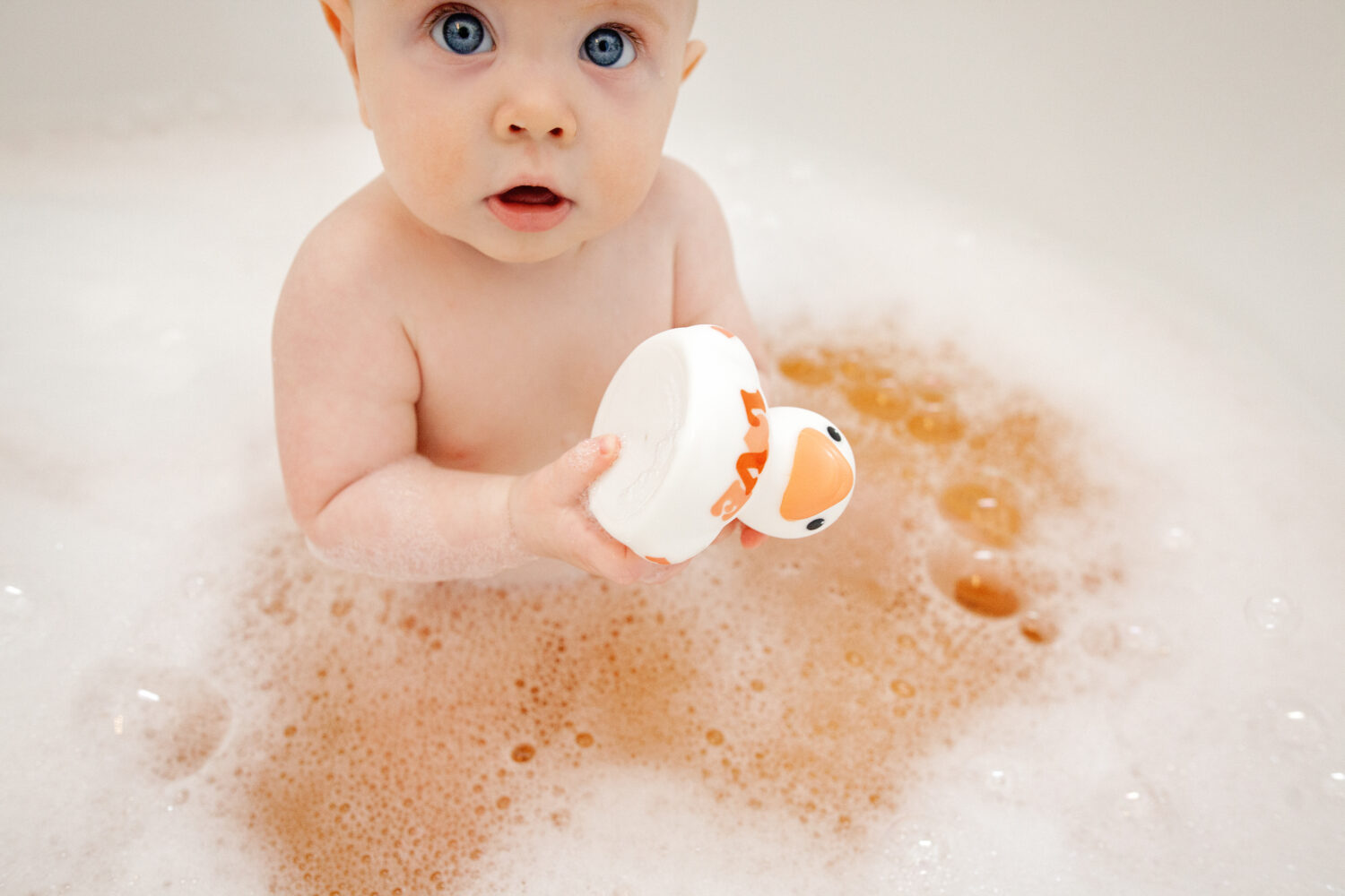 Baby boy holding Rubber duck in bathtub