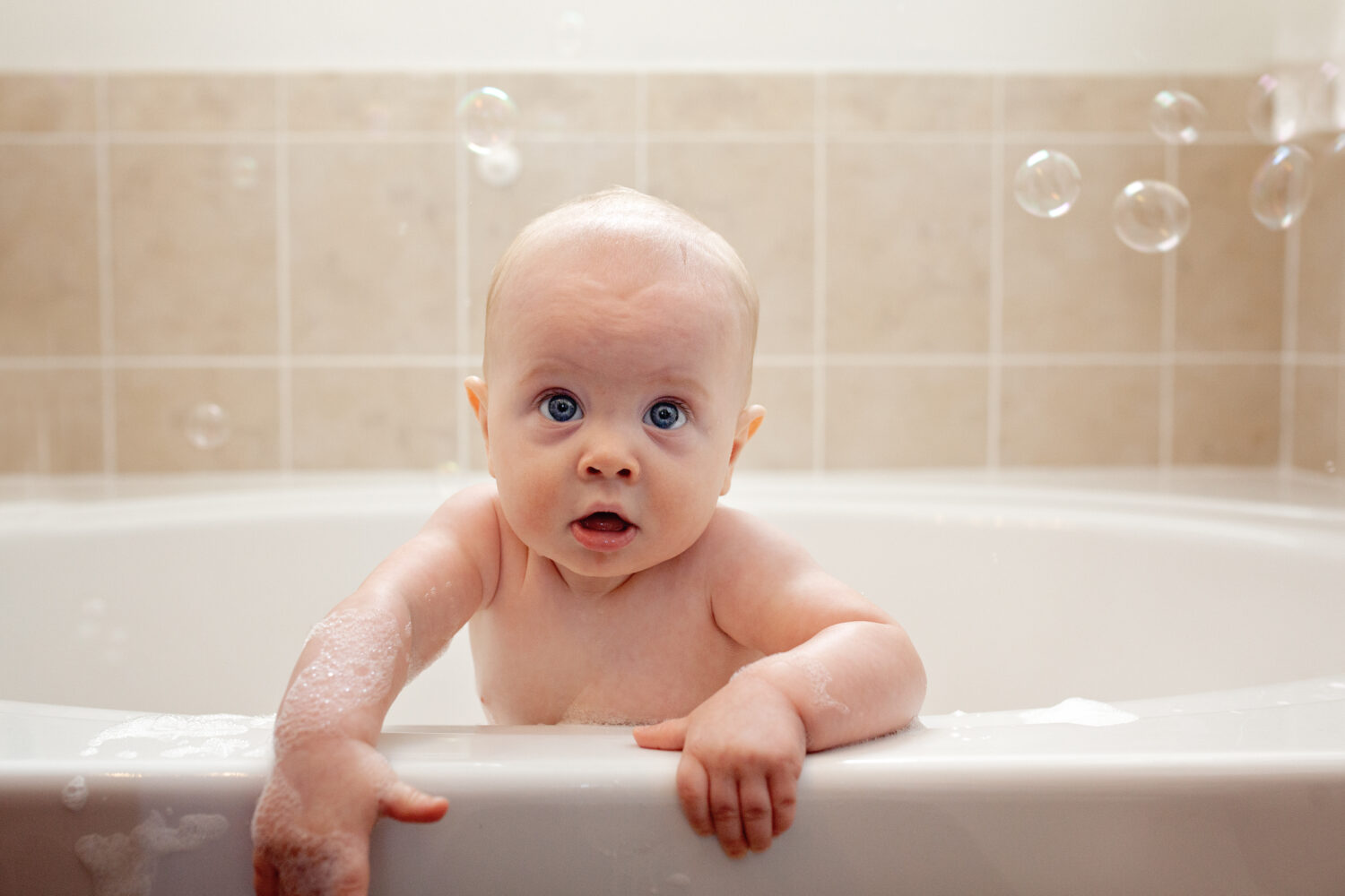 Baby leaning over the bathtub and holding on