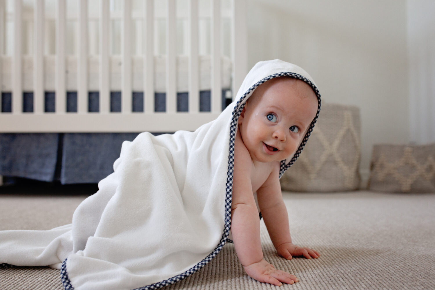 baby making the cutest face wrapped in a pottery barn towel.