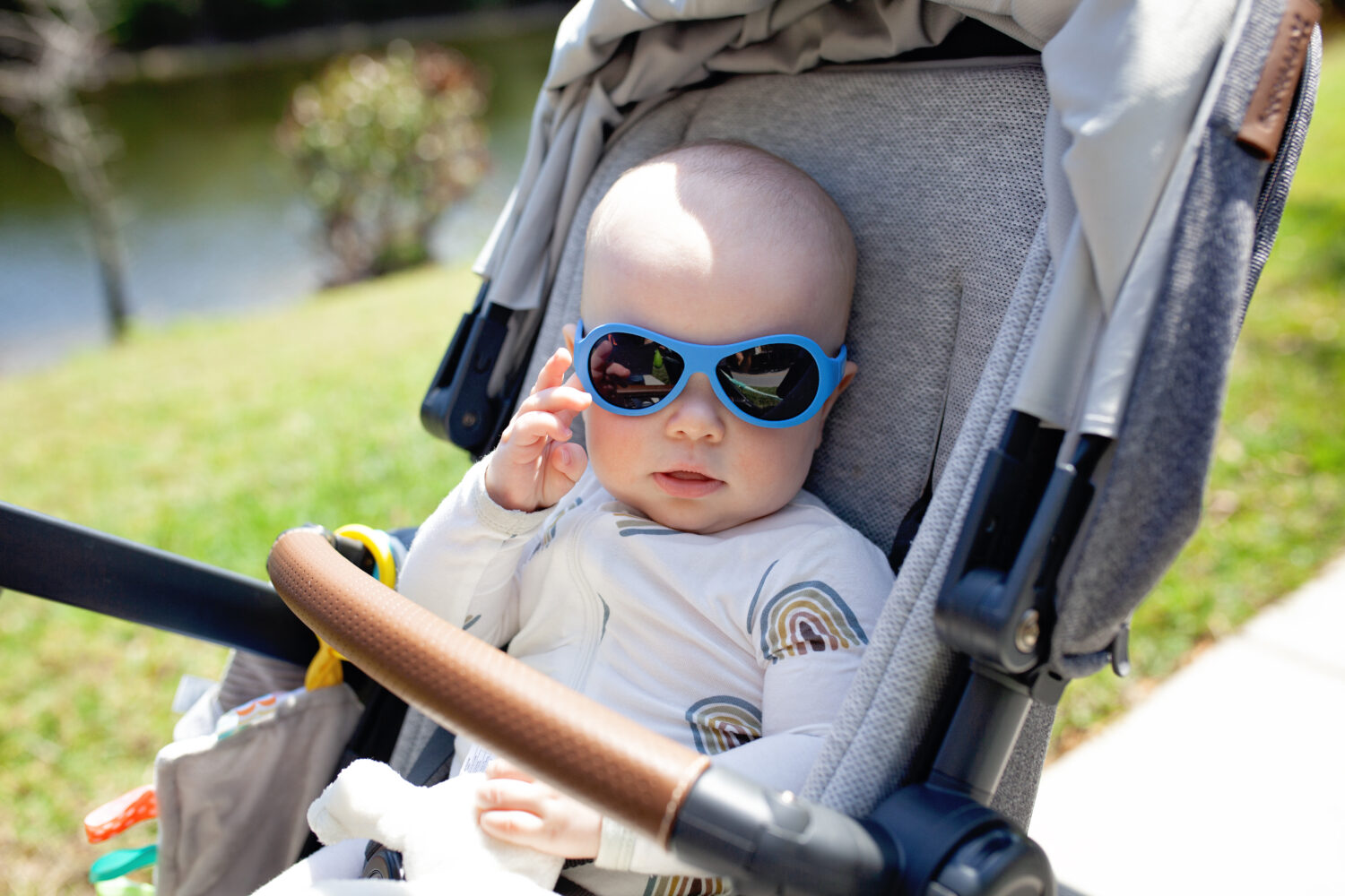 Baby in blue sunglasses sitting in his stroller chillin'