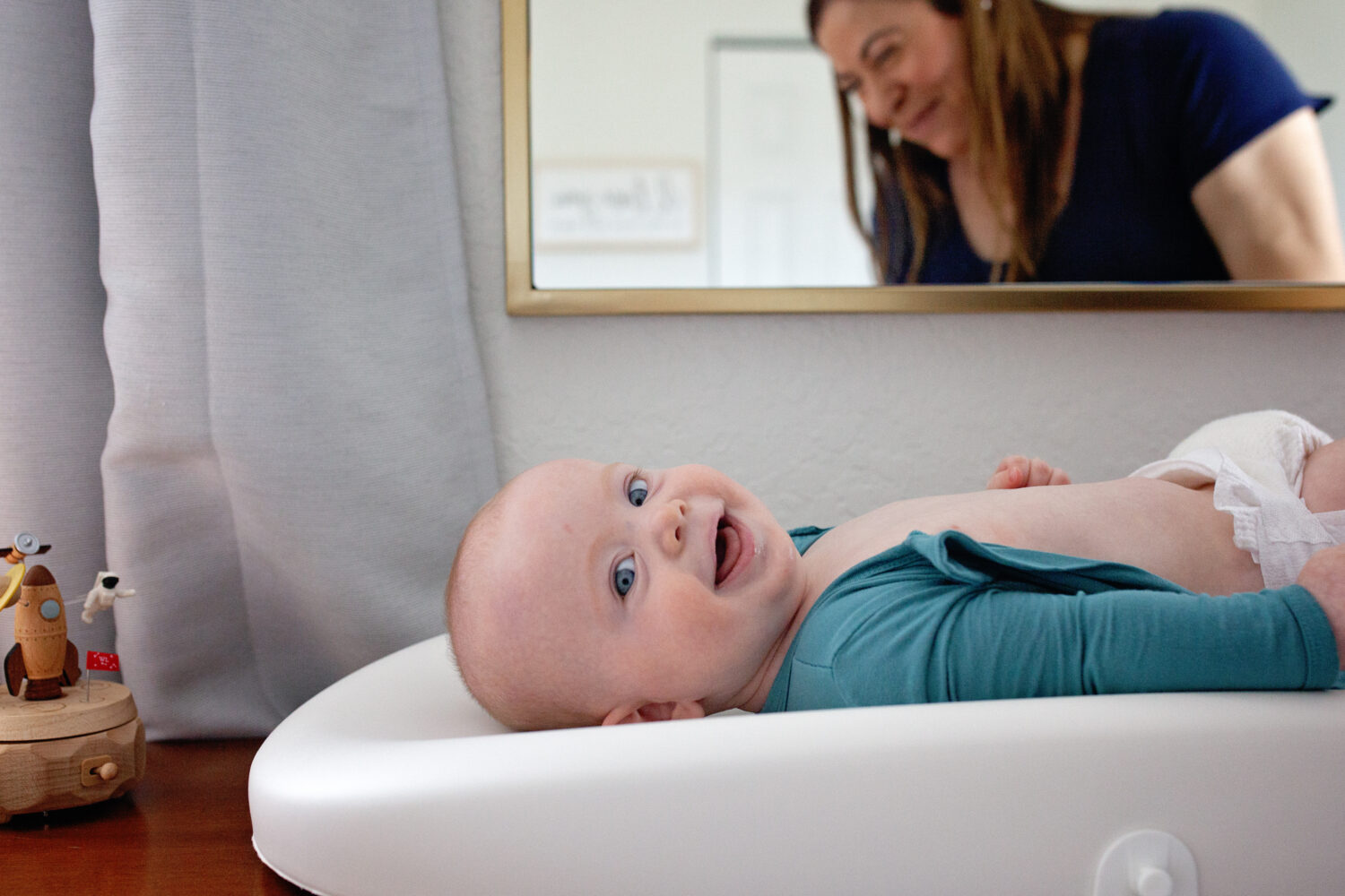 Laughing baby on changing table with mom laughing