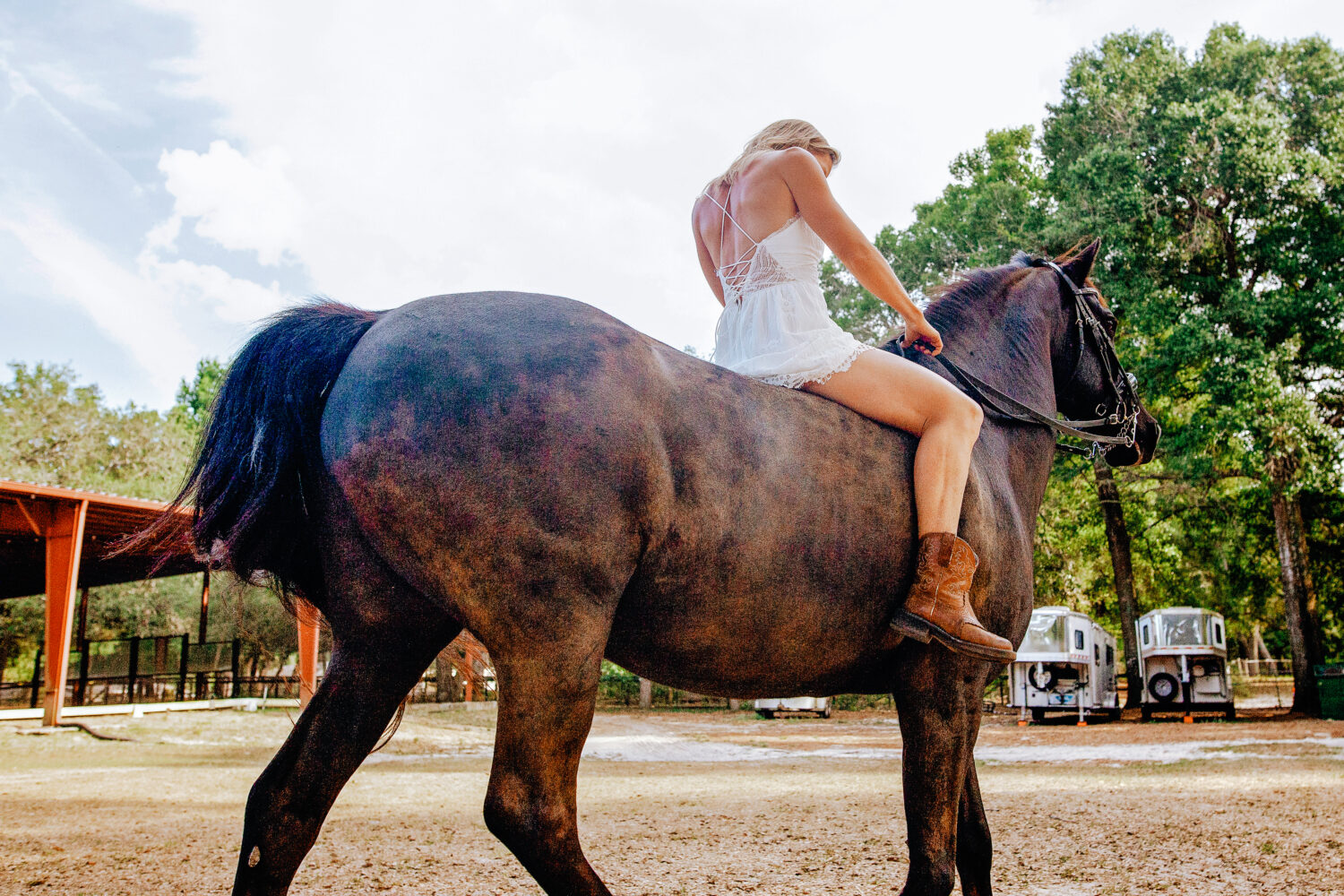 blonde lady on a brown horse riding away