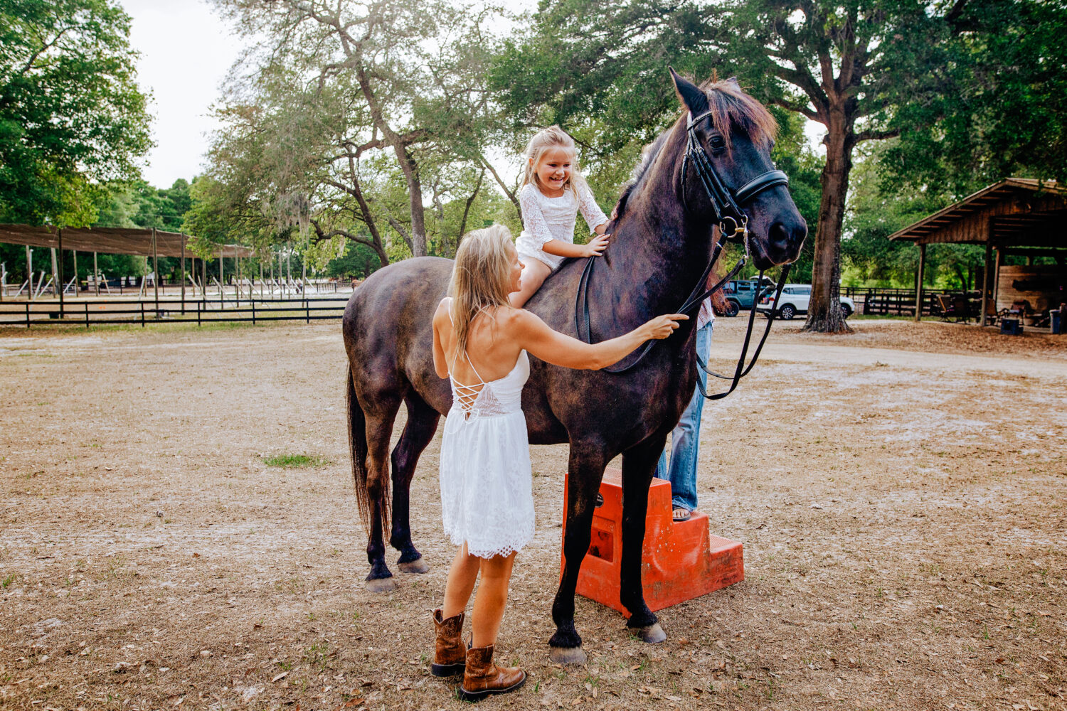 Mom and dad helping little girl get comfortable on a horse with no saddle