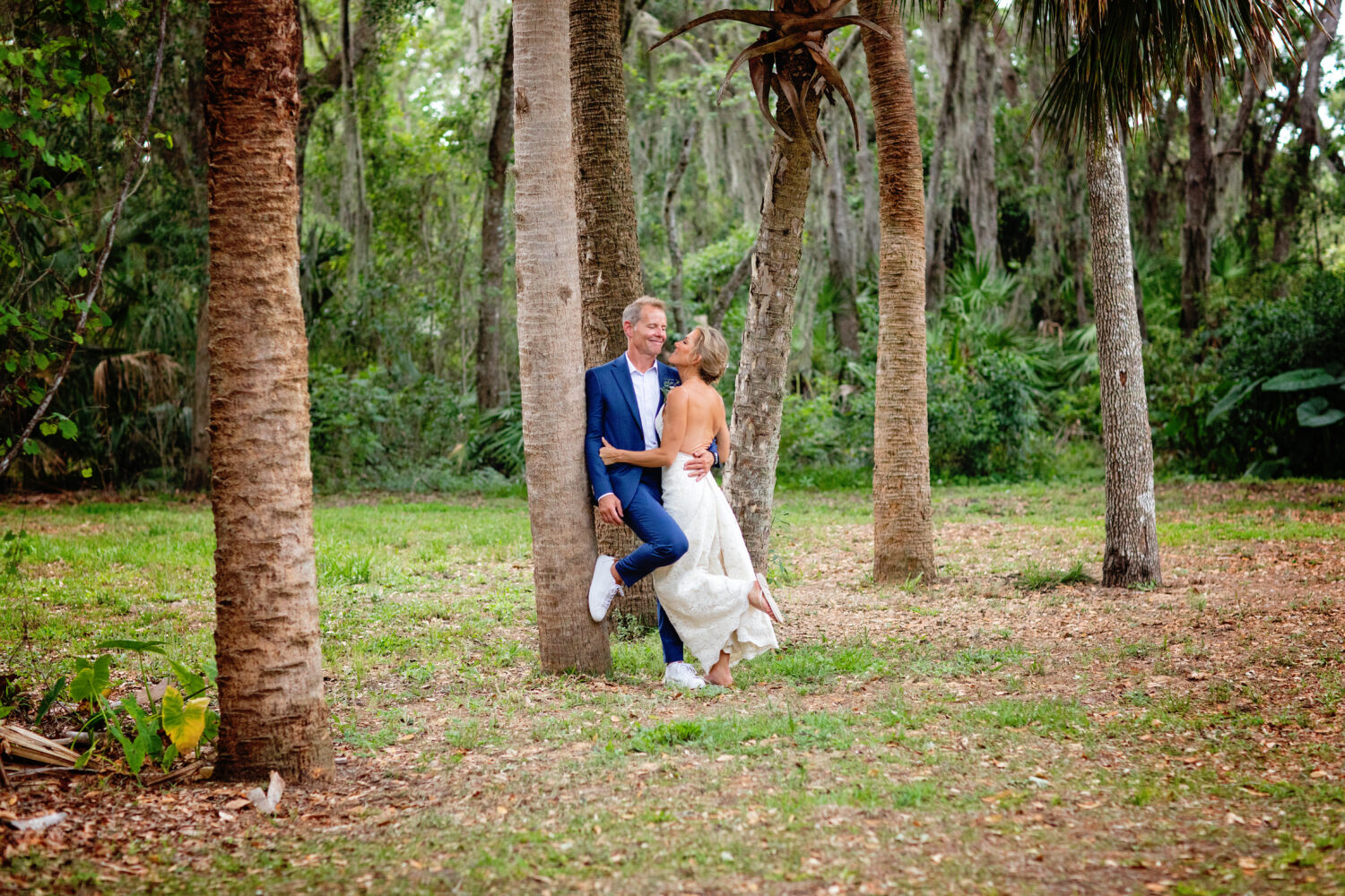 bride and groom kissing against a tree 