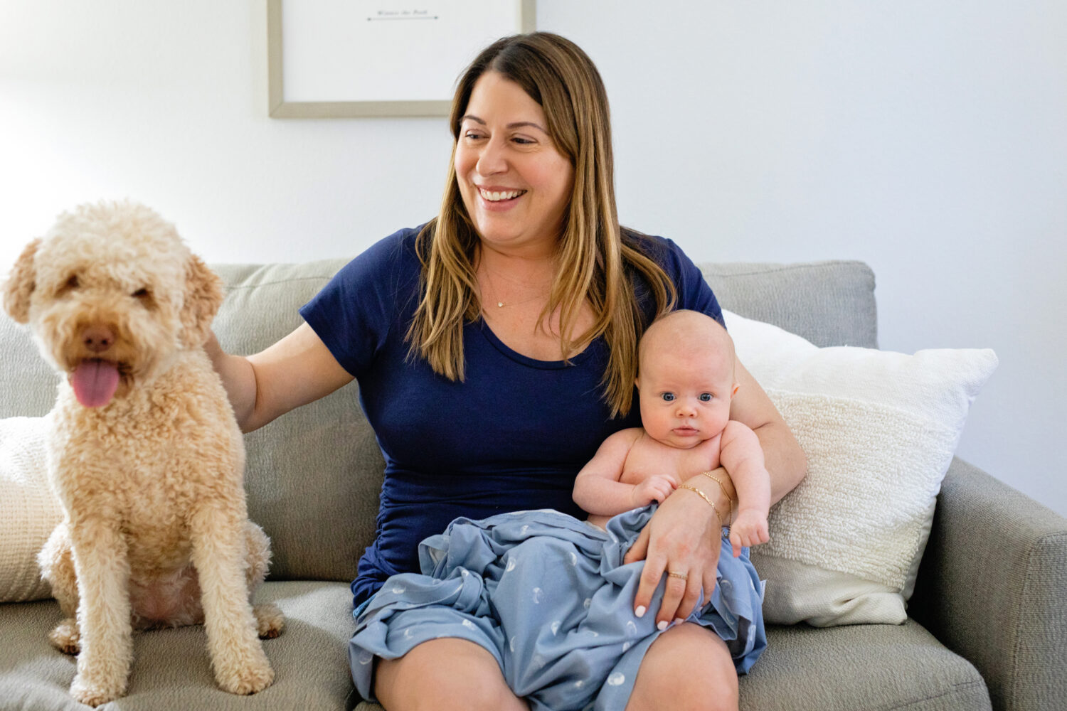 Mom, baby and dog on a couch smiling